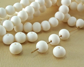May include: A strand of white round beads made from bone, with a few beads strung on a gold wire.