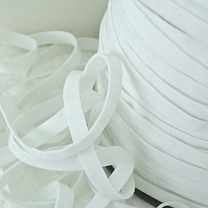 May include: A spool of white elastic cord, with a loose end of the cord in the foreground. The cord is soft and flexible, and it is perfect for sewing projects.