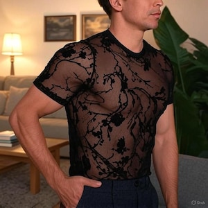 May include: Black sheer short-sleeved top with a floral design. The top features a crew neck and is made from a transparent material. The dark floral pattern is detailed, giving a delicate and stylish appearance.