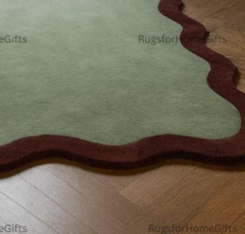 May include: A sage green rug with a wavy, dark red border. The rug is on a wooden floor. The text "RugsforHomegifts" is visible in the image.