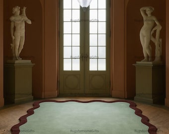 Può includere: Un interno con un tappeto verde chiaro con un bordo ondulato rosso scuro. Il tappeto è al centro di una stanza con statue, una grande porta e un lampadario. Le pareti sono color pesca caldo e il pavimento è in legno.