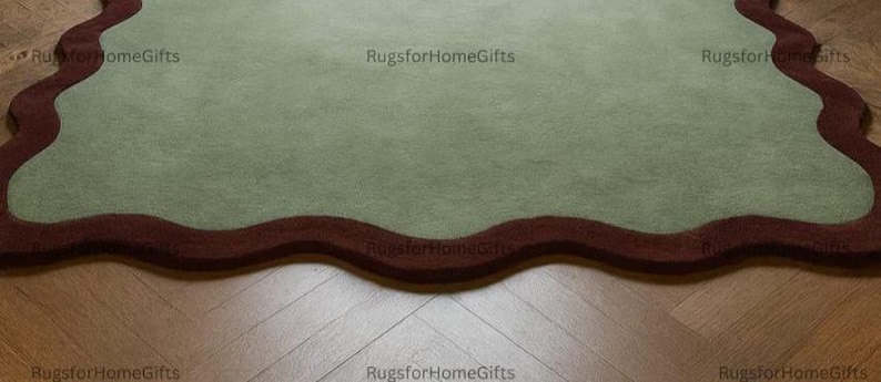 May include: A sage green rug with a wavy, dark red border. The rug is placed on a wooden floor with a herringbone pattern. The rug's unique shape and colour palette add a touch of elegance to any room. The text "RugsforHomeGifts" is visible in the corners.
