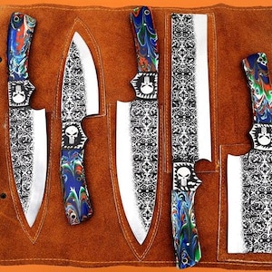 May include: A set of six stainless steel knives with decorative handles and blades. The handles feature a colorful, swirled design and a skull emblem. The blades have a detailed, ornate pattern. The knives are displayed in a brown leather knife roll.