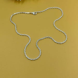 Könnte beinhalten: Ein Set aus drei Keramikbechern mit gesprenkelter, matter Oberfläche. Die Becher sind in Creme-, Hellgrau- und Dunkelgrautönen gehalten. Jeder Becher hat ein schlichtes, minimalistisches Design.