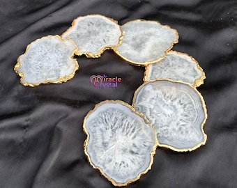 May include: A collection of agate coasters with gold-painted edges. The coasters are white and gray with unique patterns. The image includes the text "miracle crystal".