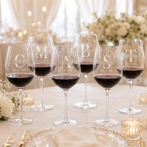 Può includere: Sei calici da vino in vetro trasparente riempiti di vino rosso, ciascuno con un monogramma bianco inciso, un cognome e la data 06.14.2026. I nomi includono Carter, Miller, Adams, Brown, Smith e Thompson, in un carattere centrato.