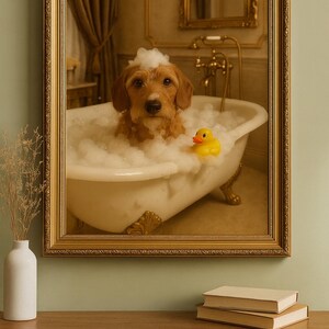 Op de afbeelding: Een ingelijste prent van een hond in een bubbelbad met een gele badeend. De hond, met bruine vacht, zit in een badkuip met klauwpoten vol bellen. De gouden lijst omringt de afbeelding, die zich in een badkamer bevindt.