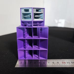May include: A purple 3D-printed speaker system with two stacked components. The lower section has a multi-compartment design, while the top features two speaker enclosures. A ruler shows the system's length is approximately 12 inches.