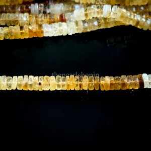 May include: Strands of citrine gemstone beads. The beads are rectangular and vary in shades of yellow and amber. The beads are strung together, creating a necklace or bracelet.
