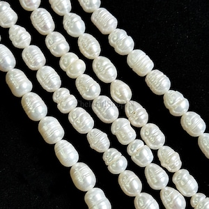 May include: Close-up of multiple strands of white, oval-shaped pearls. The pearls have a lustrous sheen and are strung together, creating a beautiful display. The background is black, highlighting the pearls.
