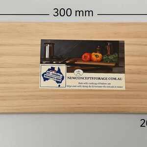 May include: A rectangular wooden chopping board, 30 cm long, 20 cm wide, and 2 cm thick, with a recessed image of a kitchen scene. The image includes tomatoes, peppers, and text that reads "NEWCONCEPTSTORAGE.COM.AU".