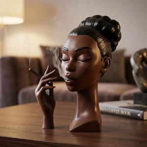 May include: A dark brown sculpture of a person with a high bun hairstyle, closed eyes, and glossy lips. The figure holds a thin, brown cylindrical object between fingers, with a wisp of white smoke rising from the tip near the mouth area.