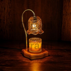 Könnte beinhalten: Dekorativer elektrischer Kerzenwärmer mit einem blütenförmigen Glasschirm. Er hat einen goldfarbenen Metallarm und steht auf einem Holzsockel. Der bernsteinfarbene Glasschirm und der Kerzenhalter weisen ein Rautenmuster auf.