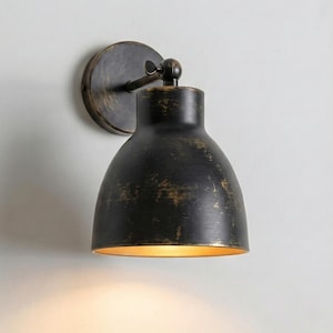 Può includere: Applique da parete nero con finitura anticata e interno dorato. L'applique ha un paralume arrotondato e una piastra di montaggio circolare. L'apparecchio è progettato per il montaggio a parete e fornisce illuminazione ambientale.