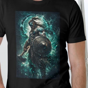Può includere: T-shirt nero con un'illustrazione dettagliata di un guerriero con scudo e ascia, su sfondo blu e verde. L'opera raffigura una figura muscolosa in una posa dinamica, creando un impatto visivo sorprendente.