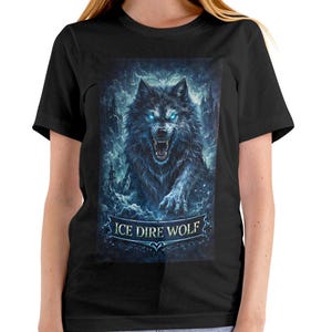Könnte beinhalten: Schwarzes T-Shirt mit einer detaillierten Illustration eines Eiswolfs mit leuchtend blauen Augen und einem knurrenden Ausdruck. Der Text "ICE DIRE WOLF" wird unter dem Wolf angezeigt. Das T-Shirt wird von einer Person getragen.