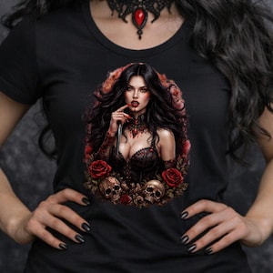 May include: Black t-shirt featuring a gothic vampire design. The graphic includes a woman with long black hair, red eyes, and a choker, surrounded by roses and skulls. The background shows a full moon and bats.