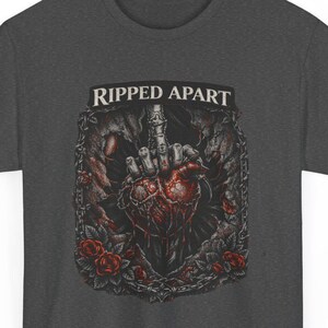 Può includere: T-shirt grigio scuro con la scritta "RIPPED APART". Il design grafico include un cuore, una mano che fa il dito medio, rose e un bordo a catena. L'opera d'arte è in tonalità di rosso, grigio e nero.