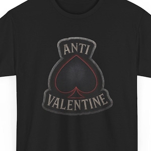 Può includere: T-shirt nero con grafica invecchiata. Il design presenta la scritta "ANTI VALENTINE" attorno a un picche nero con contorno rosso, per un look vintage e usurato.