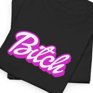 May include: Two black t-shirts are folded and stacked. The top shirt features the word "Bitch" in a white script font with a pink outline. The shirts are made of a soft material and are suitable for casual wear.