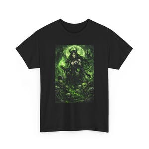 Può includere: T-shirt nero con un'illustrazione fantasy di una donna cornuta in abito nero, circondata da teschi e nebbia verde. L'immagine ha un tema gotico, con una luna piena sullo sfondo.