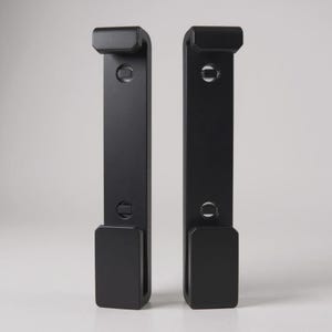 Puede incluir: Dos soportes de estante de metal negro. Cada soporte tiene una forma rectangular con una parte superior curva y una parte inferior rectangular. Los soportes están diseñados para montarse en una pared para soportar un estante.