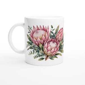 May include: White ceramic mug with a watercolour design of pink protea flowers and green foliage. The floral arrangement includes two open blooms and a closed bud, creating a botanical theme. The mug has a curved handle.