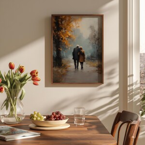 May include: A framed art print depicts an elderly couple walking on a path in a park. The artwork features a muted color palette with shades of brown, yellow, and gray. The scene is set in a park with trees and a pathway, evoking a sense of peace.
