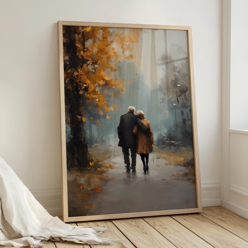 May include: Framed art print depicting an elderly couple walking arm-in-arm on a path. The painting features a muted color palette with autumn foliage in shades of gold and brown. The couple is dressed in dark coats.