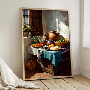 May include: A framed still life painting depicts a rustic scene with a wooden table set with pottery, fruit, and tortillas. The artwork features a blue tablecloth, terracotta pots, and a window with sunlight.