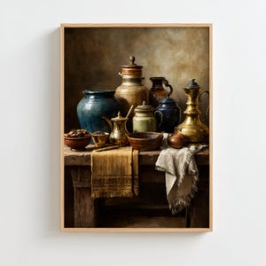 May include: A framed still life painting featuring various antique ceramic and metal vessels. The composition includes a large blue pot, a golden brass pitcher, and several smaller jars and bowls. A tan cloth and a white cloth are draped over a wooden table.
