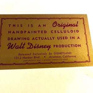 May include: A gold card with red text that reads "This is an Original Handpainted Celluloid Drawing Actually Used in a Walt Disney Production." The card also includes the text "Released Exclusively by DISNEYLAND 1313 Harbor Blvd. Anaheim, California COPYRIGHT WALT DISNEY PRODUCTIONS."