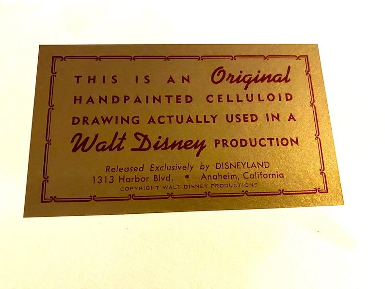 May include: A gold card with red text that reads "This is an Original Handpainted Celluloid Drawing Actually Used in a Walt Disney Production." The card also includes the text "Released Exclusively by DISNEYLAND 1313 Harbor Blvd. Anaheim, California COPYRIGHT WALT DISNEY PRODUCTIONS."