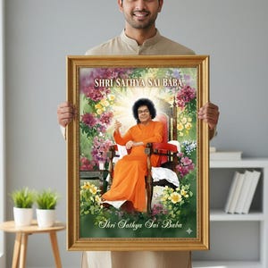 May include: A framed portrait featuring the text "Shri Sathya Sai Baba" at the top and bottom. The portrait depicts a man in an orange robe seated in a chair, surrounded by flowers. The frame is gold-colored.