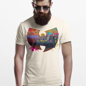 Könnte beinhalten: Cremefarbenes T-Shirt mit einer Graffiti-Illustration einer U-Bahn in einem Wu-Tang Clan Logo. Das Design verwendet lebendige Farbtöne von Orange, Lila und Blau und schafft ein kühnes und künstlerisches Statement.