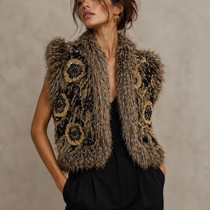 May include: A sleeveless vest featuring a brown faux fur trim along the edges and collar, layered over a black base with intricate gold and black circular embroidered floral patterns throughout the front panels and shoulders.