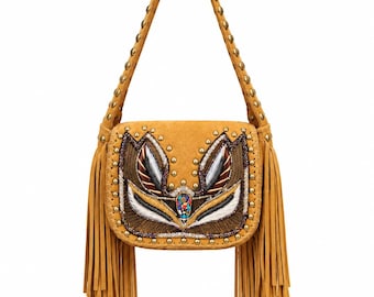 Puede incluir: Un bolso de hombro color amarillo mostaza con largos flecos en ambos lados y una correa adornada con tachuelas metálicas. La solapa frontal muestra un bordado intrincado en tonos marrón, blanco y negro, con una gema multicolor central.