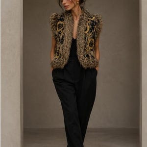 May include: A sleeveless vest featuring a textured brown faux fur finish with black and gold embroidered floral patterns on the front panels. The vest is worn over a black top and black trousers, creating a layered ensemble with a structured silhouette.