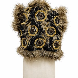 May include: A sleeveless vest featuring a black base with a textured, shaggy brown and tan faux fur trim along the edges and collar. The garment is decorated with multiple circular floral motifs embroidered with gold and dark brown beads.