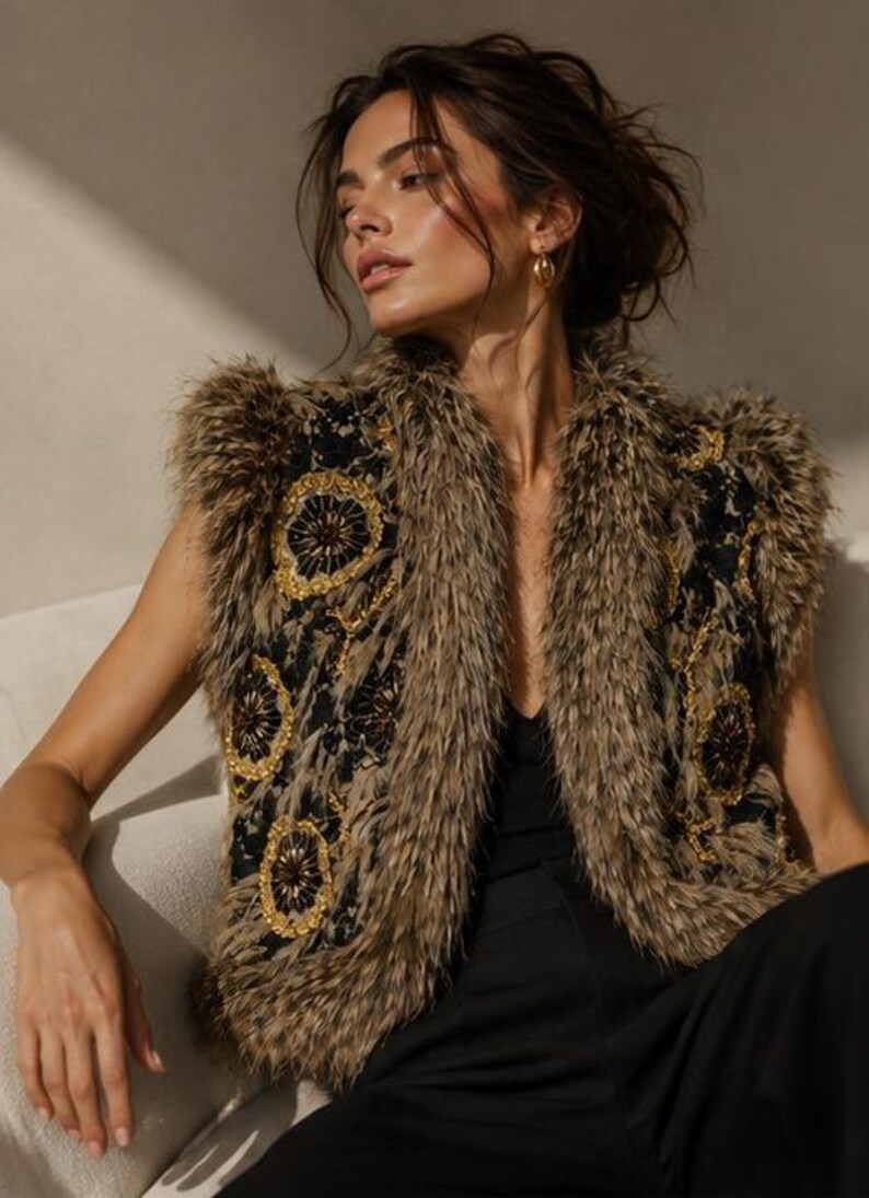 May include: A sleeveless vest featuring a black lace base with intricate gold and dark brown circular embroidery. The garment is trimmed with long, textured brown faux fur along the collar, armholes, and front edges, creating a layered appearance.