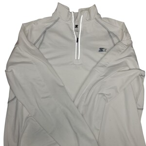 Op de afbeelding: Wit sportshirt met lange mouwen, een kwartrits en een opstaande kraag. Het shirt heeft grijze stiksels en het Starter-logo op de borst. De rits heeft een reflecterende strip.