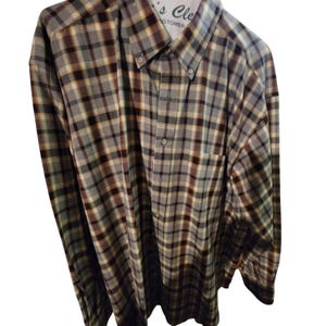 Op de afbeelding: Een button-down overhemd met lange mouwen en een ruitpatroon in grijstinten, bruin en geel. Het overhemd heeft een button-down kraag, een borstzak en manchetten met knopen. Het overhemd hangt aan een hanger.