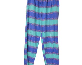 Calça retrô geométrica triangular dos anos 80/90, estilo vaporwave, nas cores verde-azulado, roxo e laranja, tamanho médio.