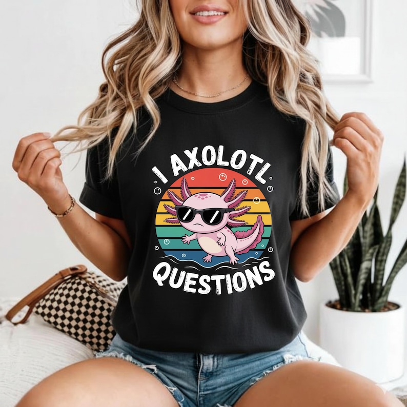 May include: Black t-shirt featuring a cartoon axolotl wearing sunglasses, set against a colorful sunset design. The text "I AXOLOTL QUESTIONS" is printed below the axolotl. A fun and quirky graphic tee.