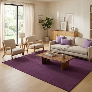 May include: A living room featuring a deep purple rug, a beige sofa, and two armchairs. A wooden coffee table is centrally placed, and a large window provides natural light. Purple cushions add a splash of colour.