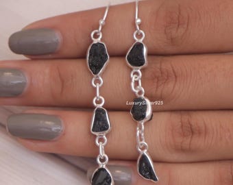 May include: A pair of dangle earrings featuring three raw, irregular black stones set in silver-toned metal links. The earrings hang vertically, with each stone encased in a simple silver frame connected by small circular jump rings. Text reads LuxurySilver925.
