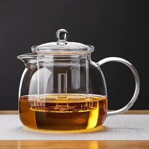 以下が含まれることがあります： 黒いハンドルと黒い太字で「But First, Coffee」の文字が入った白いセラミックマグ。マグは木製の表面に置かれています。マグの高さは10cmです。