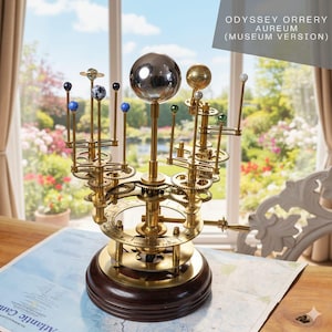 May include: An Odyssey Orrery Aureum Museum Version model featuring a large central silver sphere representing the sun, surrounded by smaller planetary spheres in various colors and sizes mounted on a brass gear mechanism atop a dark wooden base.