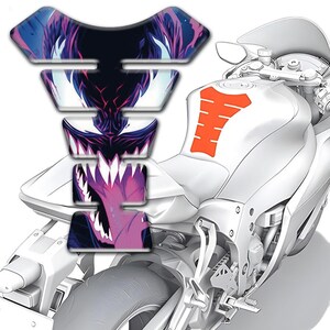 May include: A motorcycle with a white body and an orange tank protector. A multi-layered tank protector with a purple and blue graphic of a monster's face is attached to the gas tank. The motorcycle is on a white background.