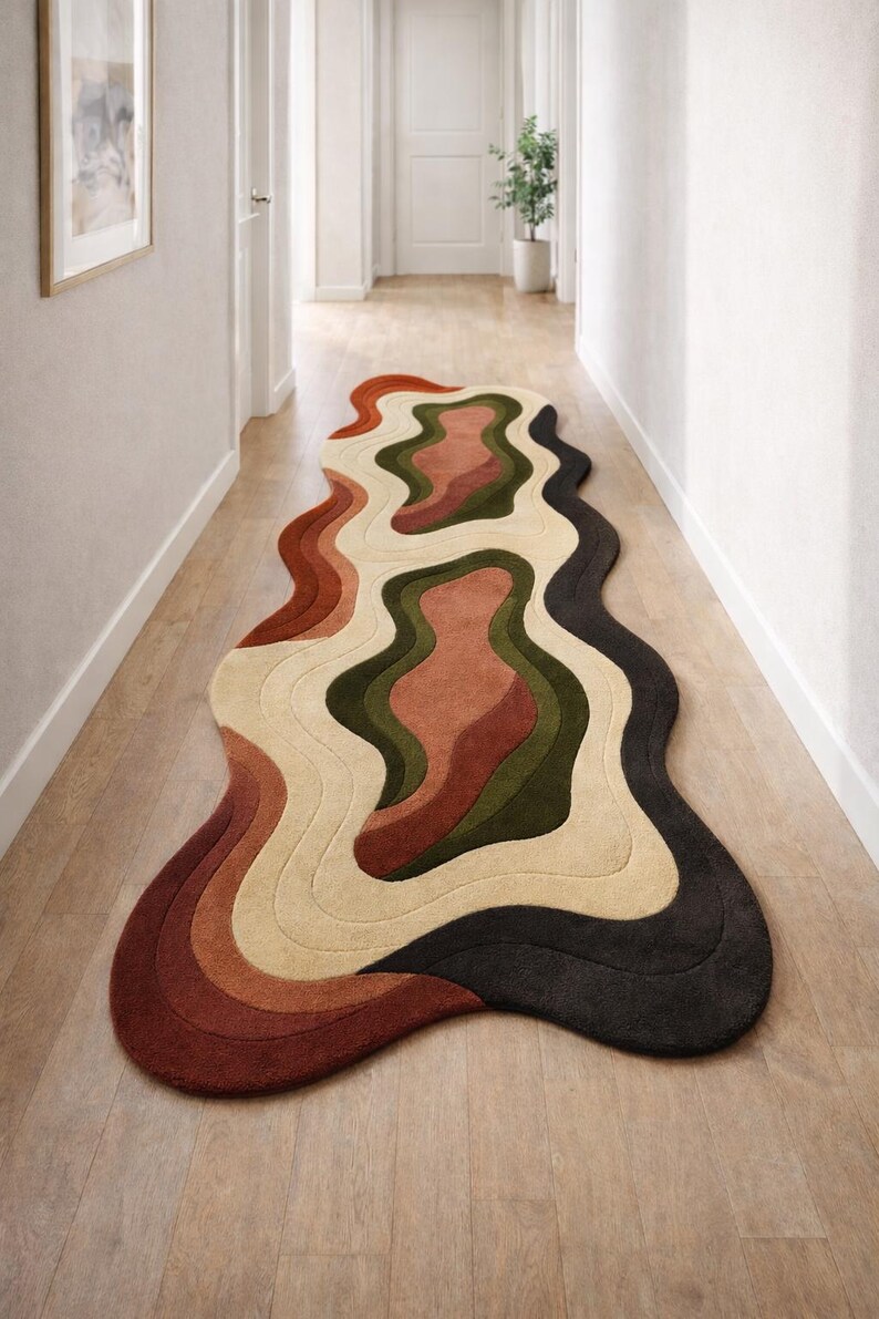 Pode incluir: Tapete abstrato com design ondulado. Apresenta uma paleta de cores quentes, incluindo tons de castanho, bege, verde e preto. Colocado sobre um ch&atilde;o de madeira num corredor, adiciona um toque moderno ao espa&ccedil;o.
